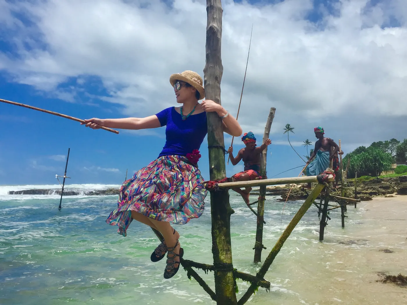 A traveller balanced on a fishing stilt beside local fishermen on the southern coast of Sri Lanka