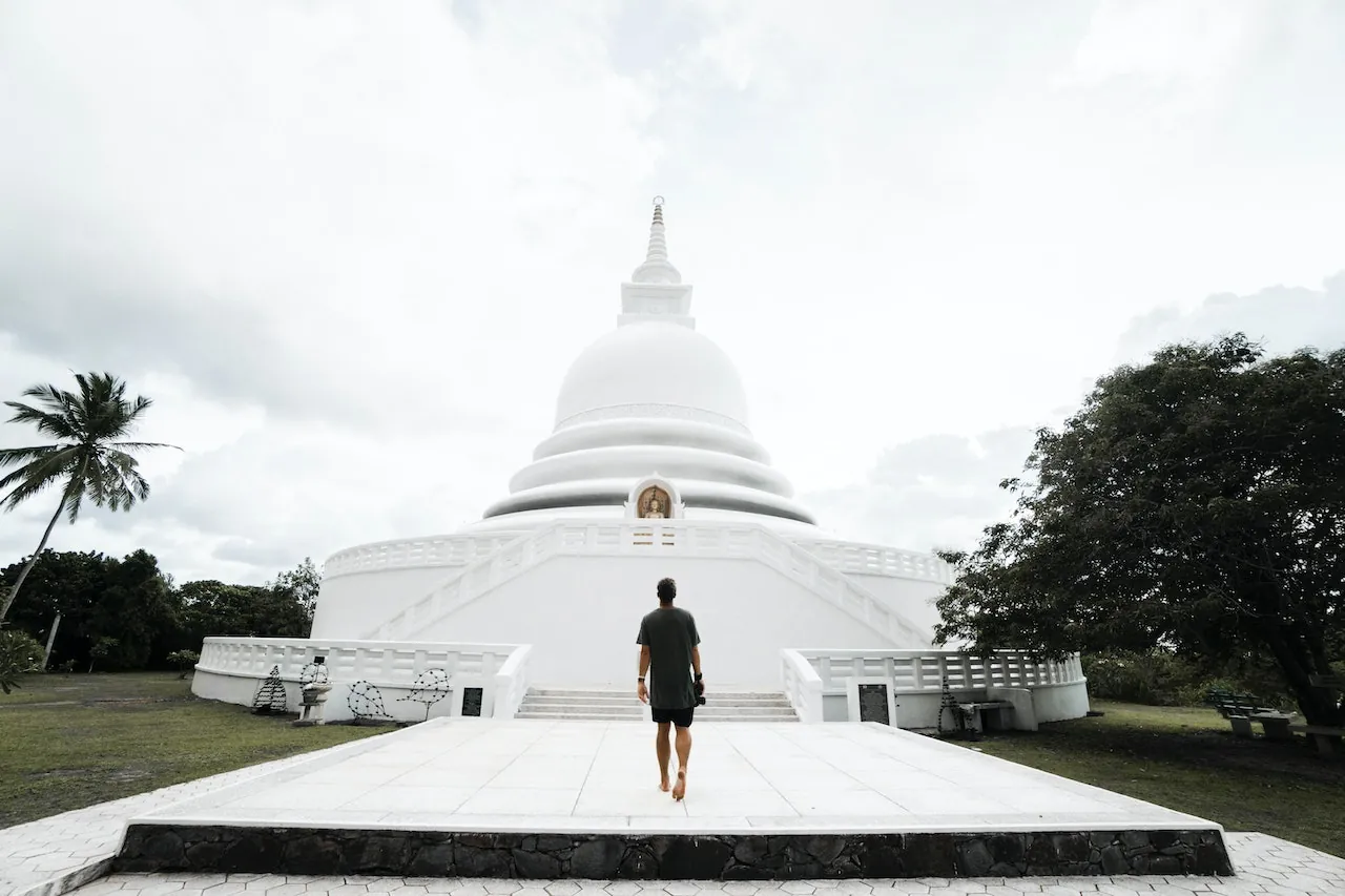 A visitor walking towards a white stupa on the Sri Lankan coast